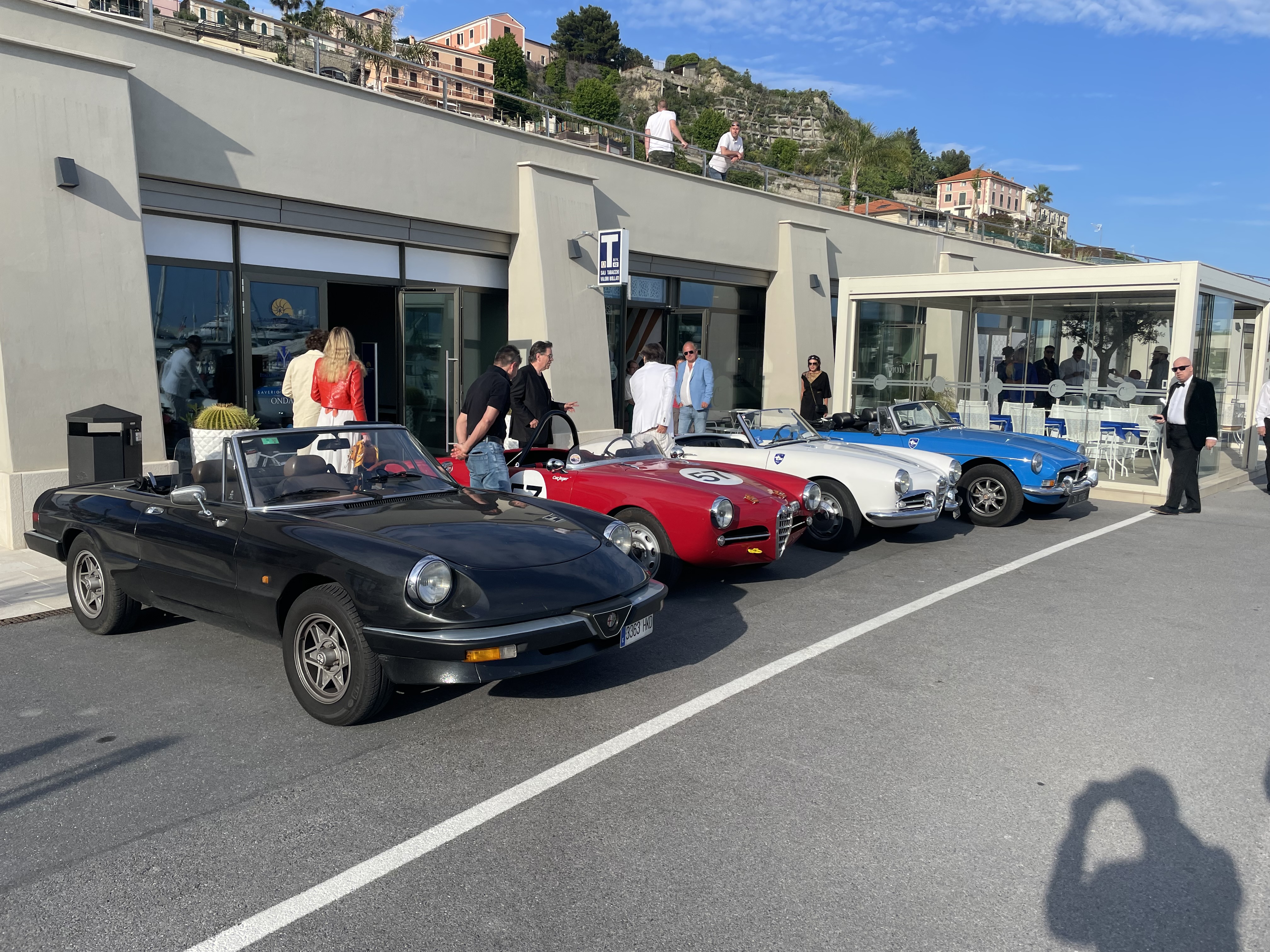 Classic Alfa Romeos lined up at a Mediterranean harbour